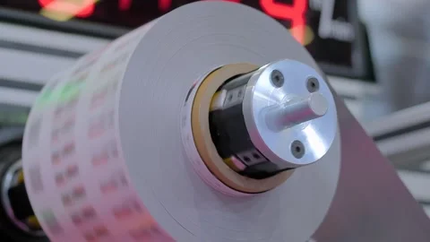 Close up: rotating printed label, trademark roll of label printing machine Stock Footage 279105545