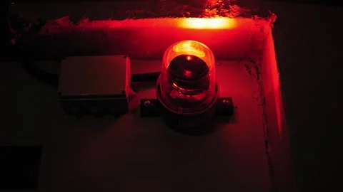 Close-up of a rotating red emergency siren lamp on the wall of a dark tunnel. Stock Footage 248342291