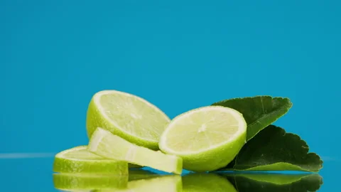 Close-up of rotating ripe limes with mint leaves on blue background, making a Stock Footage 159131351