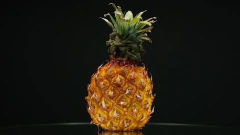 Close-up of rotating ripe pineapple on black background, making a cocktail of Stock Footage 159131189