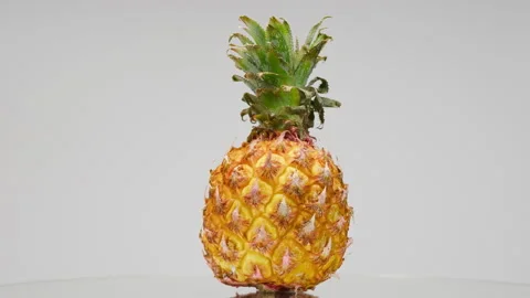 Close-up of rotating ripe pineapple on light grey background, making a cocktail Stock Footage 158931370