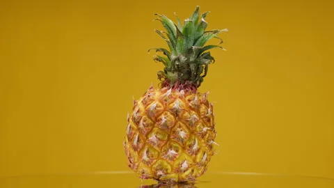 Close-up of rotating ripe pineapple on yellow background, making a cocktail of Stock Footage 159131495