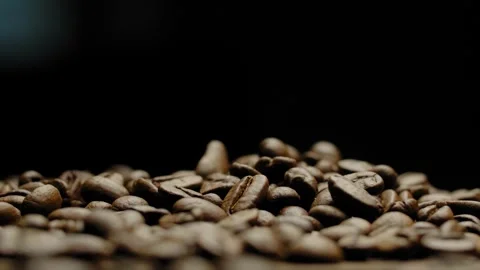 Close-up of rotating roasted coffee beans against a black background. Stock Footage 295652429