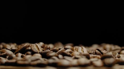 Close-up of rotating roasted coffee beans against a black background. Video stock 295652487
