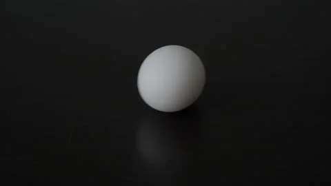 Close-up of a rotating white egg on a black table. A man's hand puts a white raw Video stock 166206259