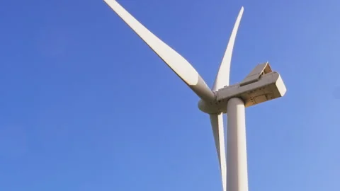 Close-Up of a Rotating Wind Turbine Against a Clear Blue Sky 動画素材 296931087