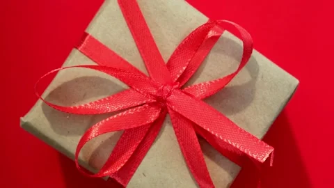 Close up rotation of gift box on red background. Minimalist Christmas concept Stock Footage 214618442