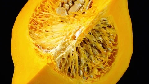 Close-up rotation of raw pumpkin quarter with seeds isolated on black. in 4K Stock Footage 74060385