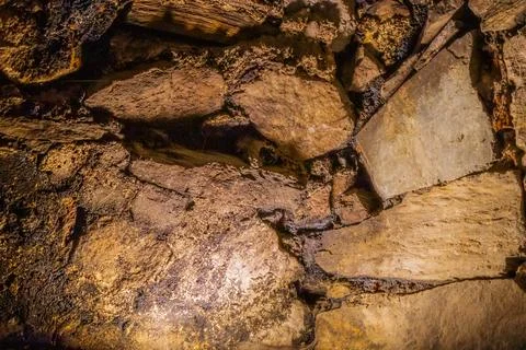 Close-up of rough ancient stone wall with golden lighting in archaeological.. Stock Photos
