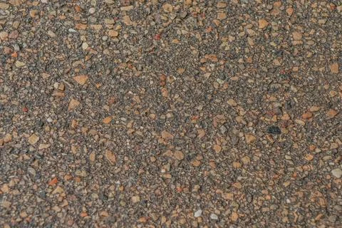 Close-up of a rough asphalt surface with small pebbles and gravel. Stock Photos