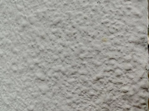 Close-up of a rough, bumpy white stucco wall texture providing an abstract Stock Photos