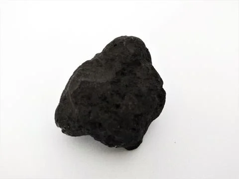 Close-up of a rough, dark volcanic rock on a plain white background Fotos Stock