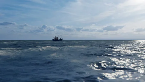 Close Up Of Rough Ocean Waves And Fishing Boat Sailing Against Blue Sky Stock Footage 147373632