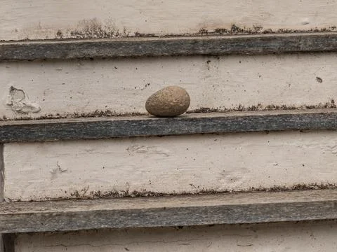 Close-up of a rough stone placed on an aged staircase with pee.. Stock Photos