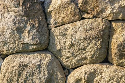 Close-up of rough stone wall texture from ancient masonry in sunlight Stock Photos