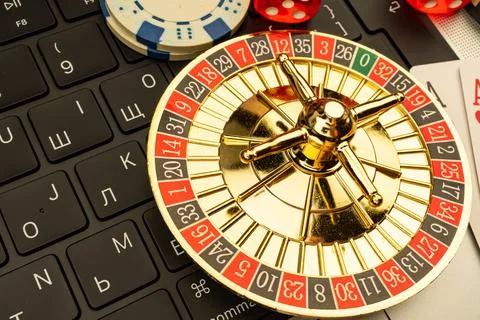 Close-up of a roulette wheel on a computer keyboard, with casino chips scat.. Stock Photos
