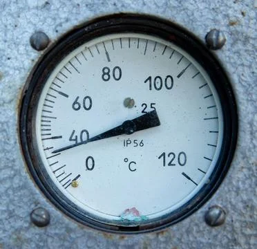 Close-up of a round analog temperature sensor mounted on a textured metal sur Stock Photos