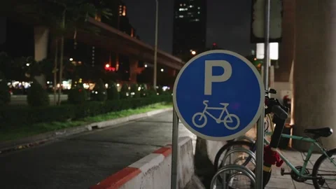 Close up of round blue bicycle parking sign on city street at night, with Stock Footage 309444701