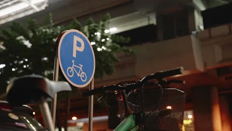 Close-up of a round blue bicycle parking sign and parked green bicycle with a Vidéo 309444739