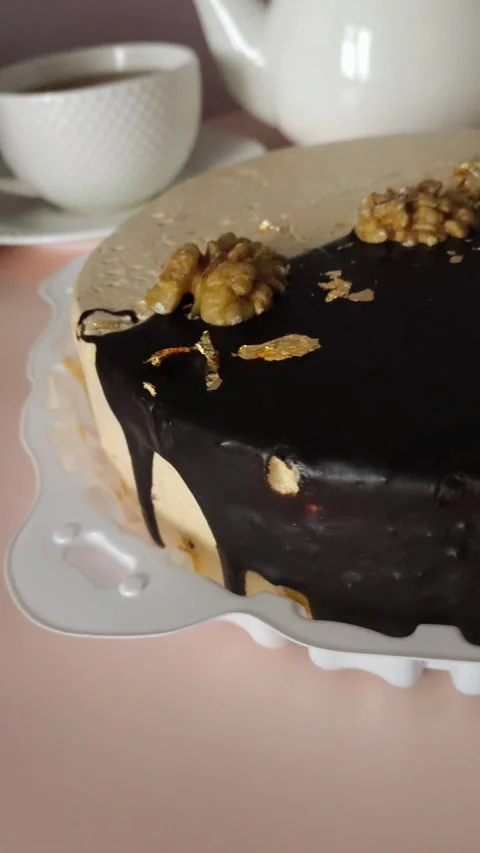Close-up of a round chocolate cake with cream and nuts on the table during a tea Stock Footage 324782576