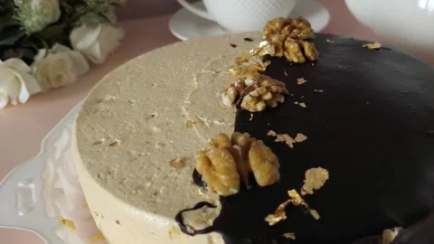 Close-up of a round chocolate cake with cream and nuts on the table during a tea Stock Footage 324782610