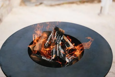 A close-up of the round frying surface with burning wood inside. Stock Photos