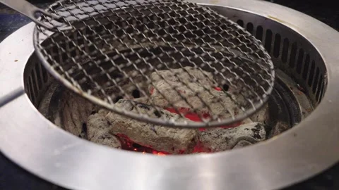 Close up of a round Korean BBQ charcoal grill with wire mesh grate and glow.. Видео 336492247