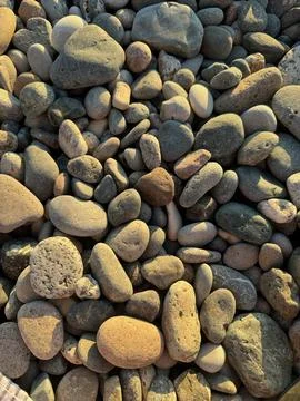A close-up of round pebbles on the beach at sunset, view from above Stock Photos