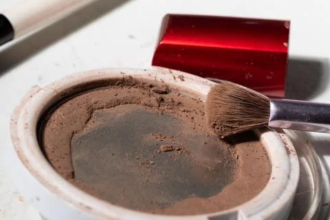 Close-up of a round powder compact with a partially used pan, visible dust, c Stock Photos