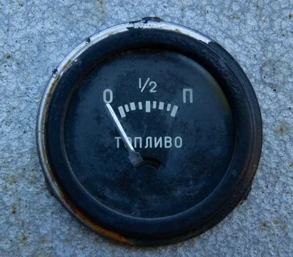 A close-up of a round, slightly worn analog fuel gauge. Stock Photos