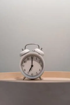 Close-up of a round white alarm clock on a table in the bedroom. Stock Photos
