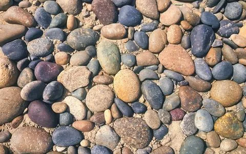 Close up of rounded river rocks and pebbles on sandy ground Stock Photos