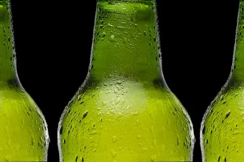 Close up row of beer bottles with drops on black background. Stock Photos