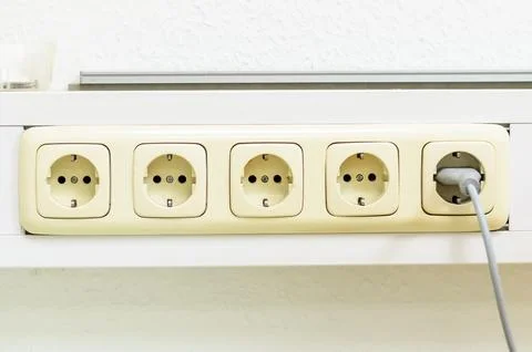 Close-up of a row of electrical outlets with a plug inserted Stock Photos