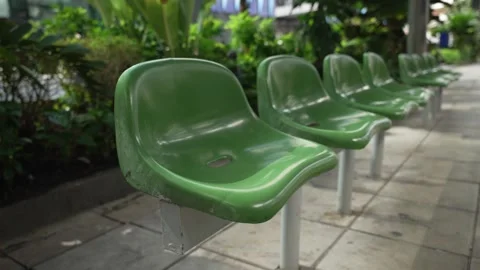 Close up of row empty green plastic seats on bus station with city street Stock Footage 310222990