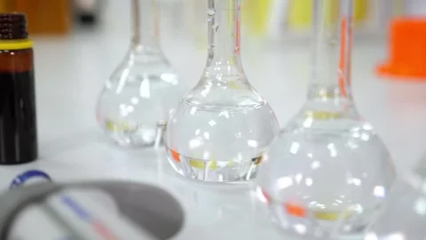 A close-up of a row of glass flasks with a transparent liquid in the laboratory. Stock Footage 288333407