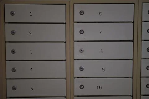 Close-up of a row of numbered metal mailboxes in a residential building lobby Stock Photos