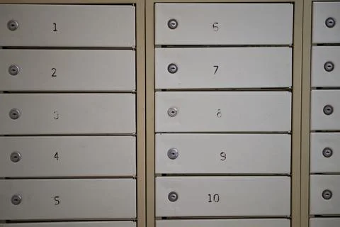 Close-up of a row of numbered metal mailboxes in a residential building lobby Stock Photos