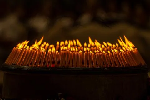 Close up rows of small burning candles capture soft smoke, flickering firel.. Foto stock