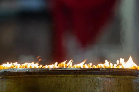 Close up rows of small burning candles capture soft smoke, flickering firel.. Foto stock