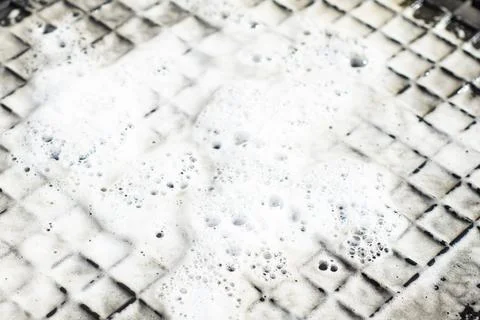 Close-up rubber grid mat covered in white soap foam and water bubbles durin.. Stock Photos