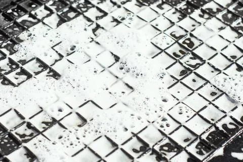 Close-up rubber grid mat covered in white soap foam and water bubbles durin.. Stock Photos