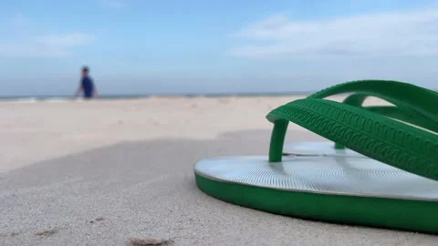 Close up rubber slippers on sandy beach, blue sky. Blurred male walking Stock Footage 206735017