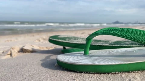 Close up rubber slippers on sandy beach, blue sky. Blurred male running Stock Footage 206736020