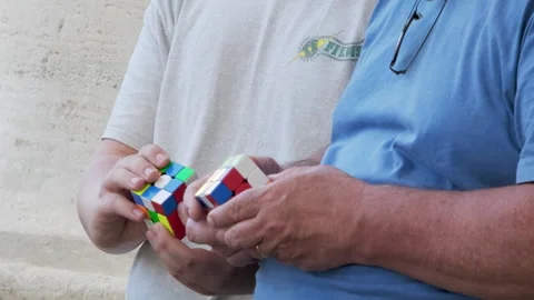 Close-up of Rubik cube in the hands of two men Stock Footage 243971577