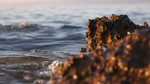 Close-up of rugged dark coastal rocks with gentle ocean waves. Stock Footage 337408576