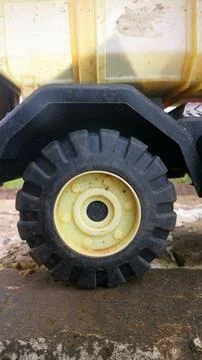 Close up of rugged plastic toy dump truck wheel on wet ground, showing chun.. Stock Photos