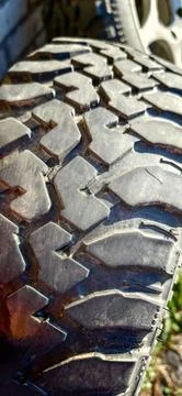 Close-up of a rugged tire tread with deep grooves and patterns, emphasizing d Stock Photos