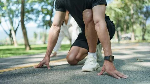 Close up of runner in crouching start position on park track for athletic sprint Stock Photos