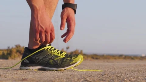 Close-up of runner with smartwatch tying trainers shoe laces outdoors Video stock 132166522